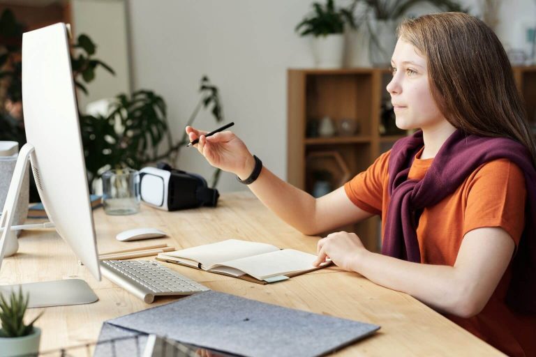girl-holding-pencil-while-looking-at-imac